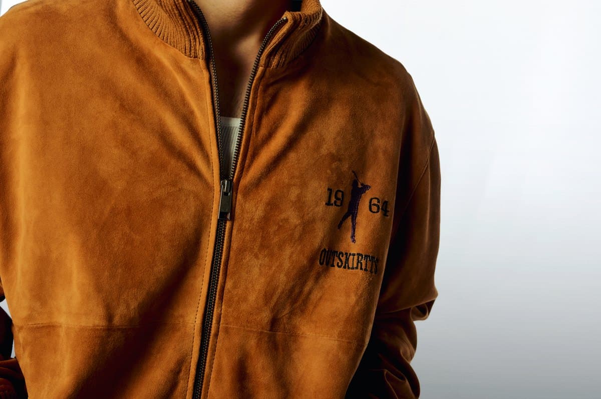 The 1964 golfer embroidered on the chest of the tan Suede Warm-Up Jacket